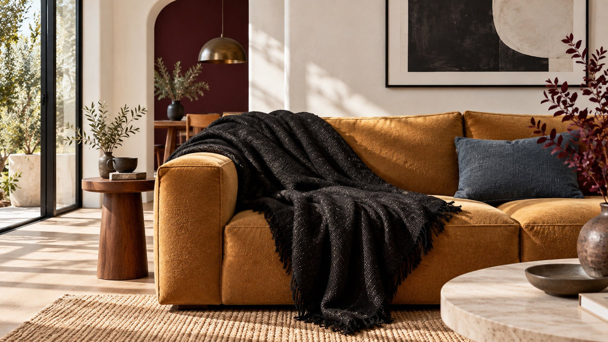 Illustration : plaid noir texturé sur un canapé ocre dans un salon clair